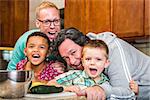 Smiling gay parents with their children in the kitchen