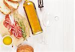 Prosciutto, wine, ciabatta, parmesan and olive oil on wooden table. Top view with copy space