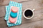 Colorful macaron cookies and cup of coffee on wooden table background
