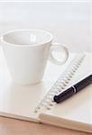 Pen and spiral notebook with coffee cup, stock photo