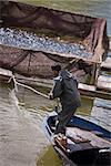 Fisherman in Toros Mounatins lake hauling in fishing nets on pontoons