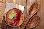 Wood kitchen utensils and spices over wooden table background