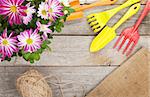Garden tools with flower on wooden table background with copy space. Focus on flowers