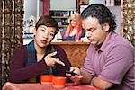 Annoyed woman pointing at cell phone held by man