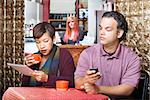 Young adult couple at cafe sneaking a peek at their devices