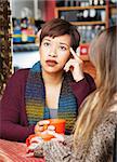 Pondering woman with friend in cafe looking up