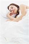 Stock image of woman sleeping in bed, white bedding