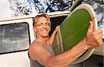 Happy man removing surfboard from of his van