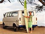 Grinning male surfer with surfboard and van on beach