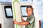 Handsome man with surfboard and wind blowing his hair