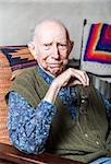 Stern elder gentleman sitting on chair in livingroom