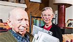 Cute elderly husband and wife reading newspapers