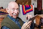 Elder gentleman working on a tablet in his living-room