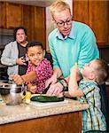 Gay couple preparing a meal with children in kitchen