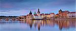 Panoramic image of Prague riverside and Charles Bridge, with reflection of the city in Vltava River.