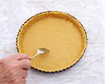 Woman finishes pricking holes in a shortcrust pastry pie crust for blind baking