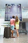 Young couple with a suitcase at the board