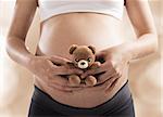 Loving pregnant woman with small teddy bear
