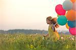 Running girl with balloons in the field