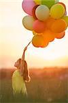 Beautiful girl with balloons in the field