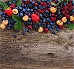 border of fresh  berries mix on wooden tabletop with copy space