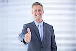 Smiling businessman giving thumbs up at the camera in the office