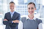 Businesswoman smiling at the camera while her colleague smiling in the background