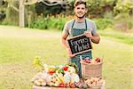 Handsome farmer standing at his stall and holding chalkboard on a sunny day