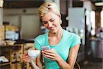 Pretty blonde woman using her smartphone with a cup of coffee at the cafe