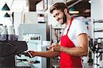 Handsome barista preparing a cup of coffee with the coffee machine