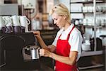 Pretty barista using the coffee machine at the cafe