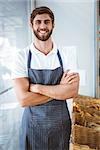 Smiling server in apron arm crossed at the bakery