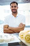 Smiling server in apron arm crossed at the bakery