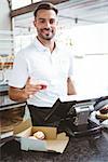 Smiling worker prepares orders at the bakery