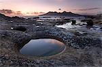 View towards Isle of Rum at sunset from rock formation at Laig Bay, Isle of Eigg, Inner Hebrides, Scotland, United Kingdom, Europe