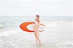 Mid adult woman standing in sea, holding surfboard