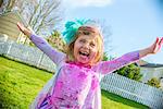 Girl in gown with feather fascinator playing outdoors