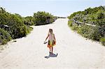 Rear view of girl walking barefoot to beach