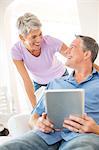 Mature couple chatting whilst using digital tablet