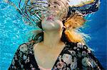 Young woman underwater, breaking through water surface