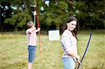 Portrait of teenage girl practicing archery with brother