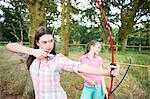 Girl and teenage sister practicing archery