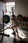 Crossfitter lifting barbell in gym
