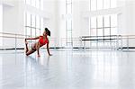 Young woman in dance studio stretching leg