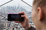 Young woman taking photo of Manhattan with her smartphone, New York City, USA