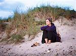 Woman sitting on sand dune