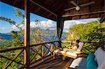 Dominica, St John Parish, Portsmouth. A young lady reads a book on the deck of a Zabuco Villa at Secret Bay. .