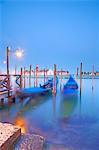 Italy, Veneto, Venice. Gondolas moored at Bacino di San Marco with San Giorgio Maggiore and the Punta della Dogana in the background.