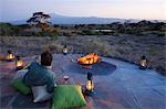 Kenya, Amboseli National Park, Tortilis Camp. A guest relaxes with a beer, overlooking Mount Kilimanjaro.