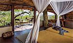 Kenya, Meru. A lady relaxes on the balcony of her luxury safari room.